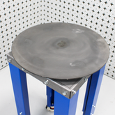 steel workbench with silver turntable on top, on a white patterned background from above